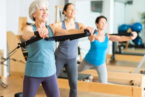 Toning Arms After 60: Empowering Womens Fitness Through Effective Weight Training 2 older woman doing weight training Knutsford and resistance in the gym to tone upper arms